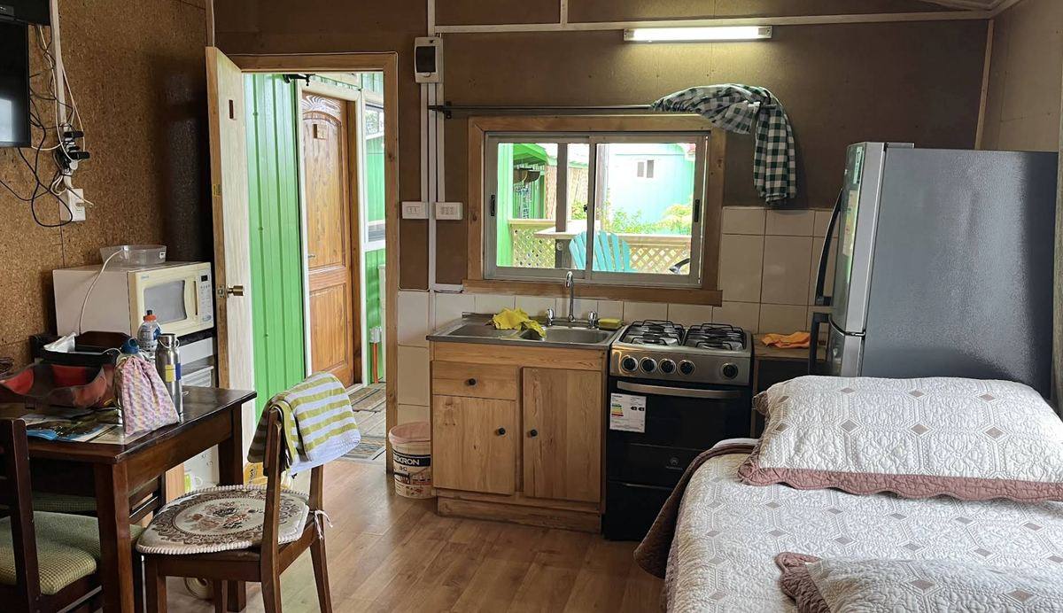 Interior de cabaña con cocina, refrigerador y cama