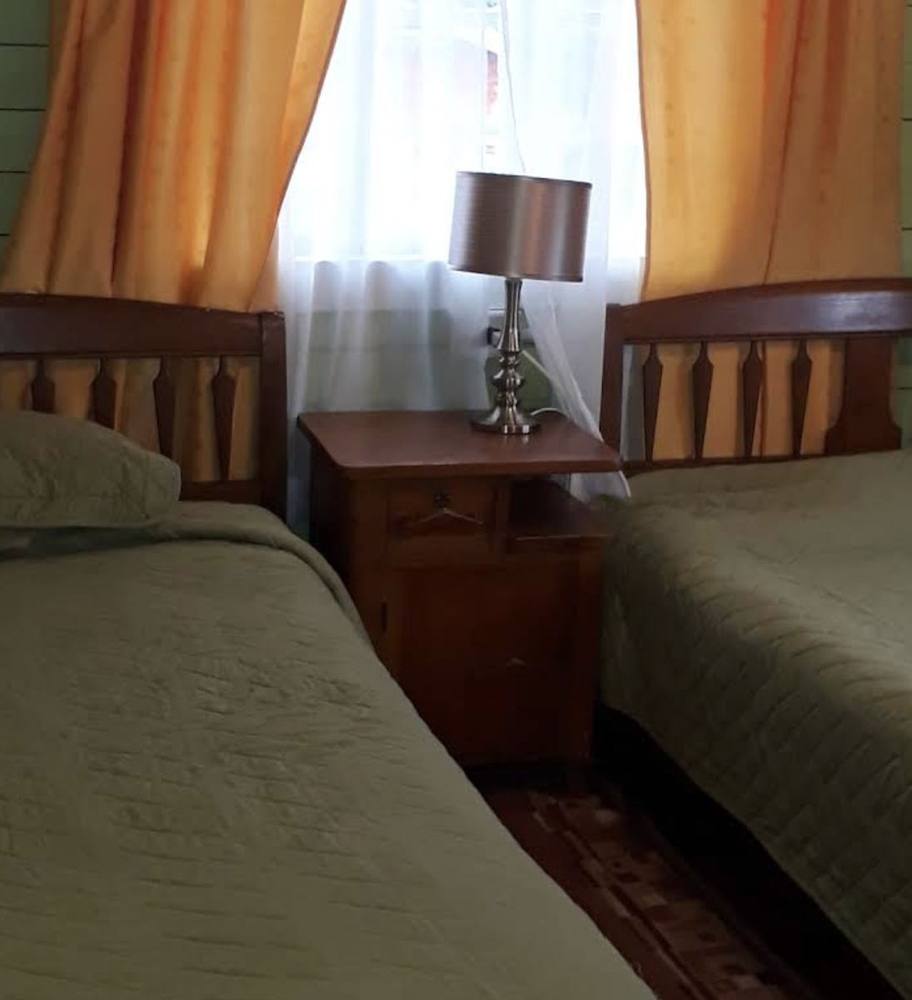Habitación con dos camas y velador de madera